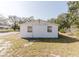A back view of a white single-story home with two windows and green space around it at 1825 134Th St, Largo, FL 33778