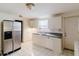 Shows a kitchen with stainless steel refrigerator, white cabinets, and tile flooring at 1825 134Th St, Largo, FL 33778