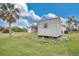 Home's backyard with green lawn, screened in porch, shed and mature trees at 7280 Meroni Blvd, North Port, FL 34291