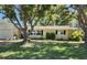 Inviting one-story home featuring manicured lawn, mature trees and neutral exterior at 1825 Alberta Dr, Clearwater, FL 33756