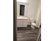 Bright bathroom featuring a vanity with a sink and toilet, complemented by wood-look flooring at 11856 Throttle Pl, Gibsonton, FL 33534
