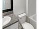 Bathroom with granite vanity top, white toilet, and white tiled shower at 15729 Fort Island Pl, Sun City Center, FL 33573