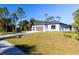 A single story home with a three car garage sits on a grassy lot with a long driveway, with tree lined backdrop at 4313 Appleton Ter, North Port, FL 34286