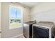 Functional laundry room with modern washer and dryer, ample natural light, and shelving at 13001 Pennybrook Dr, Riverview, FL 33579