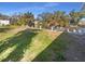 Scenic view of the grassy backyard with a pond, mature trees, and tropical landscaping at 1540 David Pl, Englewood, FL 34223