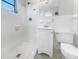 Modern white-tiled bathroom featuring a walk-in shower, vanity sink, and toilet at 1540 David Pl, Englewood, FL 34223