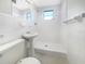 Bright bathroom featuring a pedestal sink and walk-in shower with crisp white tiles at 1540 David Pl, Englewood, FL 34223