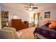 Bright bedroom with carpeting, ceiling fan, dresser, and a window with bright orange curtains at 5769 E Price Blvd, North Port, FL 34288