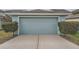 Front view of the light blue two-car garage with surrounding green plants at 6160 Castleton Hollow Rd, Riverview, FL 33578