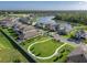 An aerial view shows houses in a neighborhood across from a green common area and pond at 12654 Oak Hill Way, Parrish, FL 34219