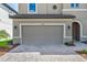 Two-car garage of a tan home with a paver driveway and well manicured front yard at 12654 Oak Hill Way, Parrish, FL 34219