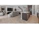 Open-concept living room with tile floors, kitchen island, gray sectional, and staircase at 12654 Oak Hill Way, Parrish, FL 34219