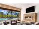 Cozy outdoor living area with stone fireplace, TV, and comfortable seating, overlooking a pool at 6237 Plateau Ct, Bradenton, FL 34203