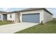 Exterior view showcasing the driveway and well-maintained lawn and blue garage door at 31673 Wild Grape Sw Ln, Brooksville, FL 34602