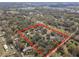 Aerial view showcasing a large property with a pond and bordered by lush, mature trees at 3634 Apfel Rd, Wesley Chapel, FL 33543