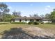 Charming single-story home featuring a screened porch, complemented by lush landscaping and mature trees at 3634 Apfel Rd, Wesley Chapel, FL 33543