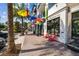 Inviting street view with colorful umbrellas strung above a sidewalk lined with shops and palm trees at 840 Virginia St # 202, Dunedin, FL 34698