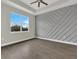 Bright bedroom features hardwood floors, large windows, a ceiling fan, and an accent wall at 15741 Autry Cir, Port Charlotte, FL 33981