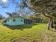 Back of the house features a screened-in porch, a large yard, and mature trees at 5275 Miller Bayou Dr, Port Richey, FL 34668