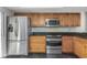 Modern kitchen featuring stainless steel appliances, wood cabinets, and black tile flooring at 13794 Marseilles Ct, Clearwater, FL 33762