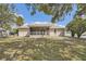 A sunny backyard view showcases a screened-in porch, perfect for enjoying the outdoors in comfort at 7001 Heath Dr, Port Richey, FL 34668