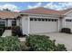 Beige house featuring a two-car garage with a tile roof and manicured landscaping at 1830 San Silvestro Dr, Venice, FL 34285