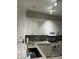 Bright kitchen featuring white cabinetry and granite countertops, offering a functional design at 1830 San Silvestro Dr, Venice, FL 34285