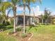 Landscaped backyard featuring a screened-in porch and lush green grass, perfect for outdoor entertaining at 4949 Sandy Glen Way, Wimauma, FL 33598
