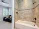 A well-lit bathroom with tiled walls and an open doorway with partial view of bedroom at 4949 Sandy Glen Way, Wimauma, FL 33598