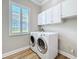 Modern laundry room with side by side appliances and wall mounted cabinetry at 4949 Sandy Glen Way, Wimauma, FL 33598