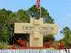 Community entrance featuring the Deep Creek sign, landscaping, and an American flag at 469 Chubut Ct, Punta Gorda, FL 33983