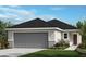 Charming single-story home featuring a gray garage door, modern architectural details and professionally landscaped front yard at 2194 Nass Rd, Zephyrhills, FL 33540