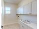 Laundry room with bright cabinets, a sink, and a view from the window at 5013 Sea Branch Ave, Apollo Beach, FL 33572