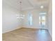 Bright and spacious living room with wood-look flooring, stylish chandeliers, and large windows at 5013 Sea Branch Ave, Apollo Beach, FL 33572