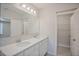 Bathroom featuring double sink vanity with framed mirror and walk-in closet at 25880 Prada Dr, Punta Gorda, FL 33955