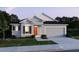 Charming single-story home with a well-manicured lawn, a two-car garage, and a welcoming orange front door at 27210 Adams St, Punta Gorda, FL 33983