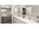Bright bathroom featuring double sinks, white cabinetry, and a view of the bedroom through an open doorway at 2349 Broadpoint Dr, Punta Gorda, FL 33983
