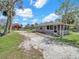 Quaint home with screened porch and gravel driveway, complemented by lush green lawn and mature trees at 8123 Double Branch Rd # 1, Tampa, FL 33635