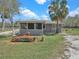 Charming home with a screened-in porch, set amid a green lawn and mature palm trees under a sunny sky at 8123 Double Branch Rd # 1, Tampa, FL 33635