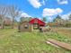 Rustic red barn and shed, accented by scattered logs and pallets, set against a verdant green backdrop at 8123 Double Branch Rd # 1, Tampa, FL 33635