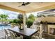 Covered patio features an outdoor kitchen, dining table, and a scenic pool view at 4914 Carova Way, Lakewood Ranch, FL 34211