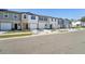 View of a row of townhomes with varied facades, green lawns, and a paved street, showcasing curb appeal at 6148 Pina Colada St, Zephyrhills, FL 33542