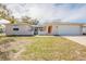 Charming single-story home featuring an attached garage, red front door, and a well-maintained lawn at 9811 Rainbow Ln, Port Richey, FL 34668