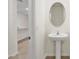 Modern half bathroom with pedestal sink, oval mirror, and neutral wall paint at 32859 Pez Landing Ln, Wesley Chapel, FL 33543