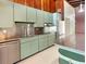 Functional kitchen featuring retro-green cabinetry, stainless steel appliances, and a breakfast bar for casual dining at 513 Flamingo Dr, Apollo Beach, FL 33572