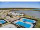 Aerial view of community with a lake, clubhouse, pool, and tennis courts on a sunny day at 17936 Polo Trl, Bradenton, FL 34211