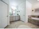 Bright bathroom with a double sink vanity, soaking tub with tile surround, and neutral color palette at 17936 Polo Trl, Bradenton, FL 34211
