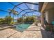 Beautiful screened pool with a spa, surrounded by swaying palms and vibrant tropical plants at 17936 Polo Trl, Bradenton, FL 34211