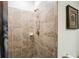 Tiled shower featuring bronze hardware, a built-in shelf, and decorative artwork at 17936 Polo Trl, Bradenton, FL 34211