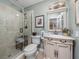 Well-lit bathroom with a marble shower, framed mirror, sink and toilet at 650 Poinsettia Rd, Belleair, FL 33756